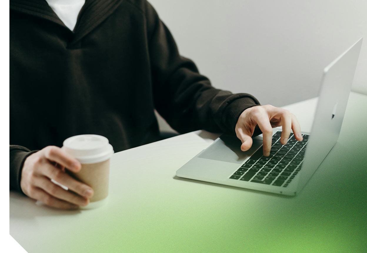 A person typing on a laptop while holding a coffee cup, symbolizing focused work and productivity
