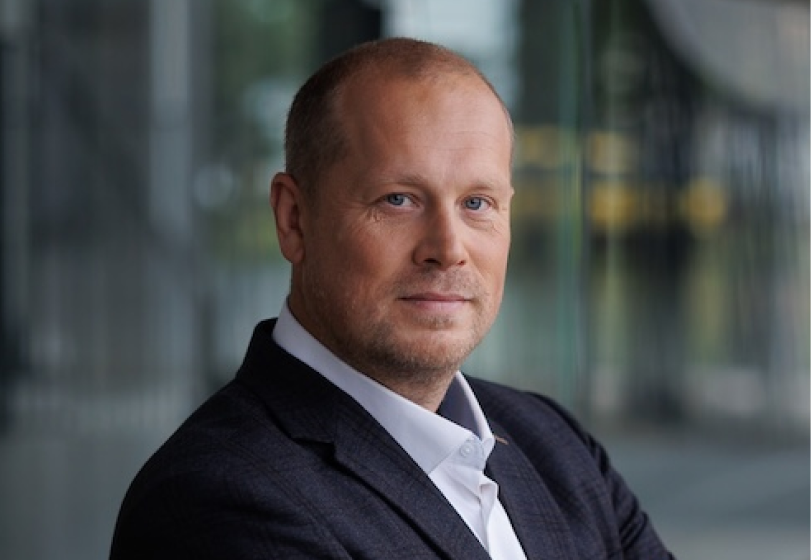 Man in business suit posing outdoors with confident expression and blurred urban background