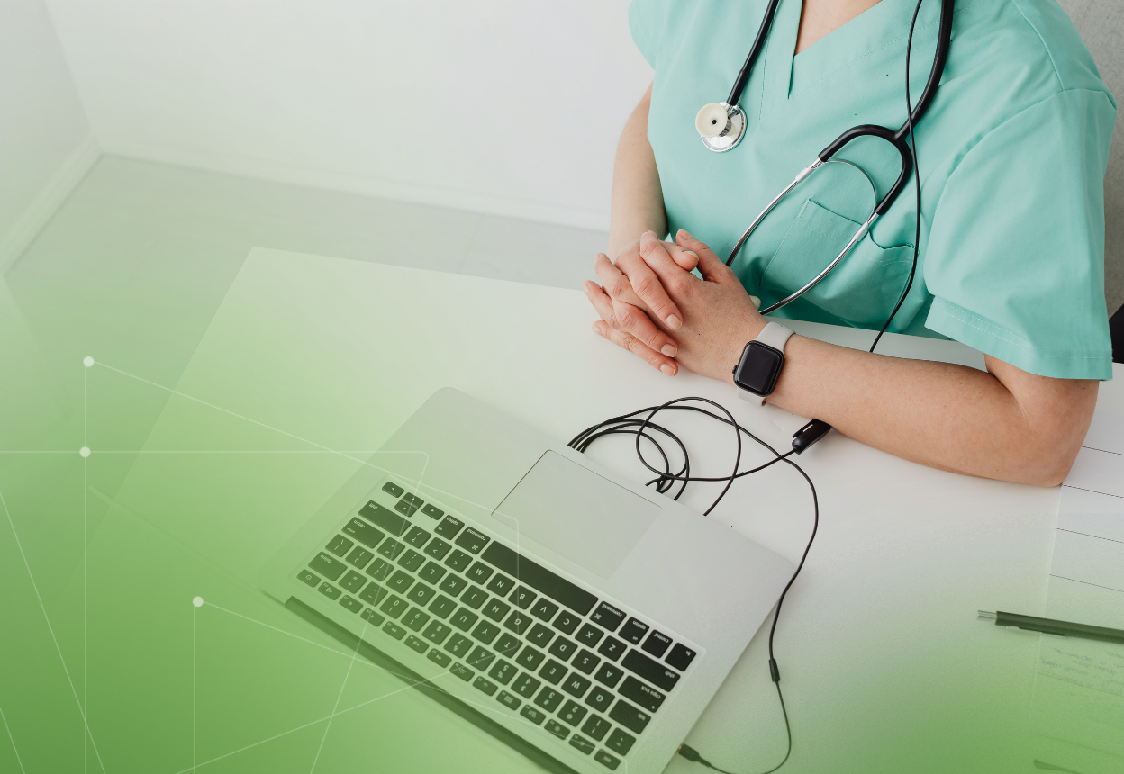A nurse is sitting at a table with a laptop