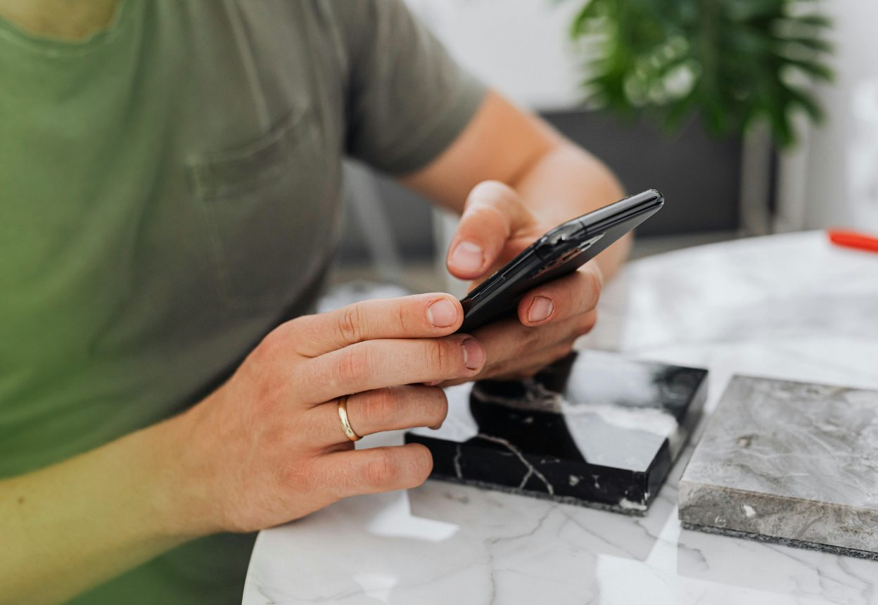 A man is sitting at a table, holding a phone
